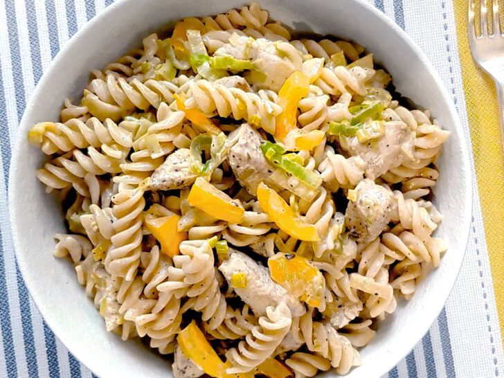 Creamy chicken and leek pasta in a white bowl.