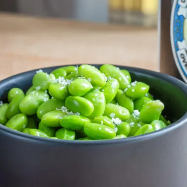 Microwaved edamame in a black bowl.