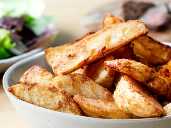 A bowl of air fried frozen potato wedges.