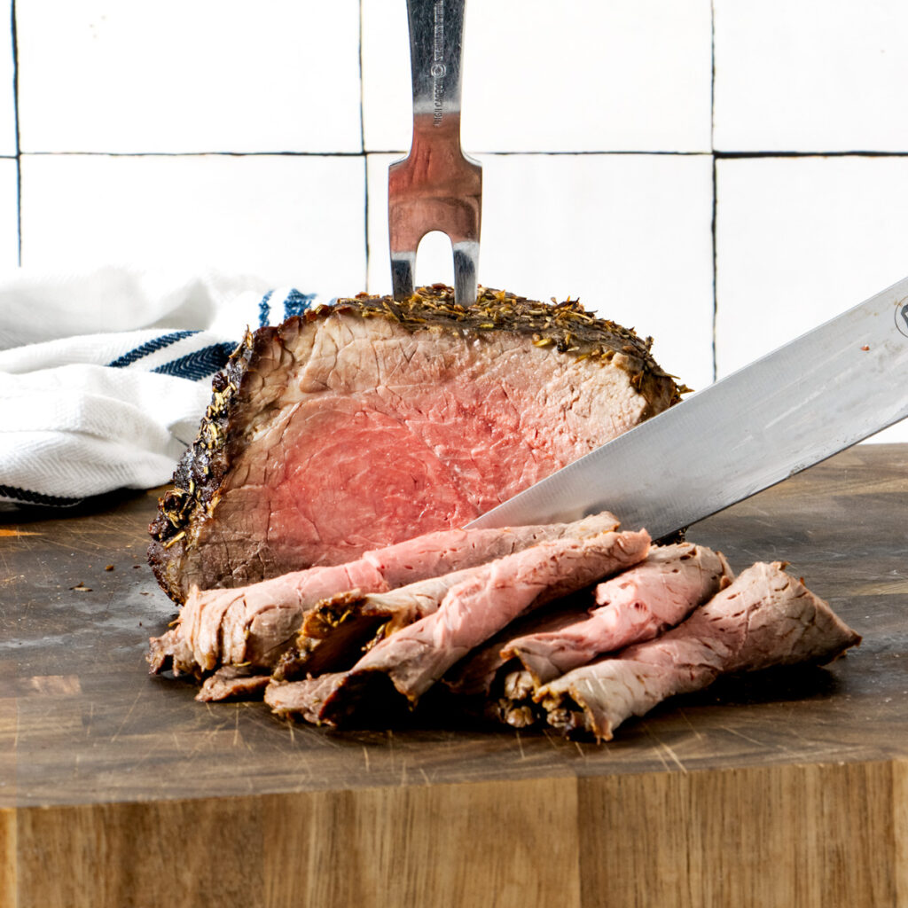 Air fryer roast beef, sliced on a wooden board. 