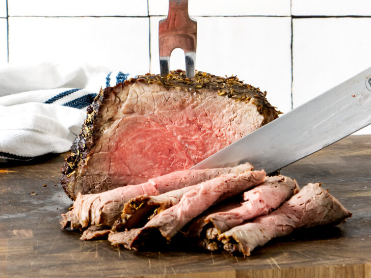 Air fryer roast beef, sliced on a wooden board.