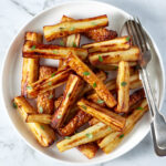 Air fryer pasnips on a white serving dish.