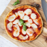 Air fryer pizza on a wooden board.