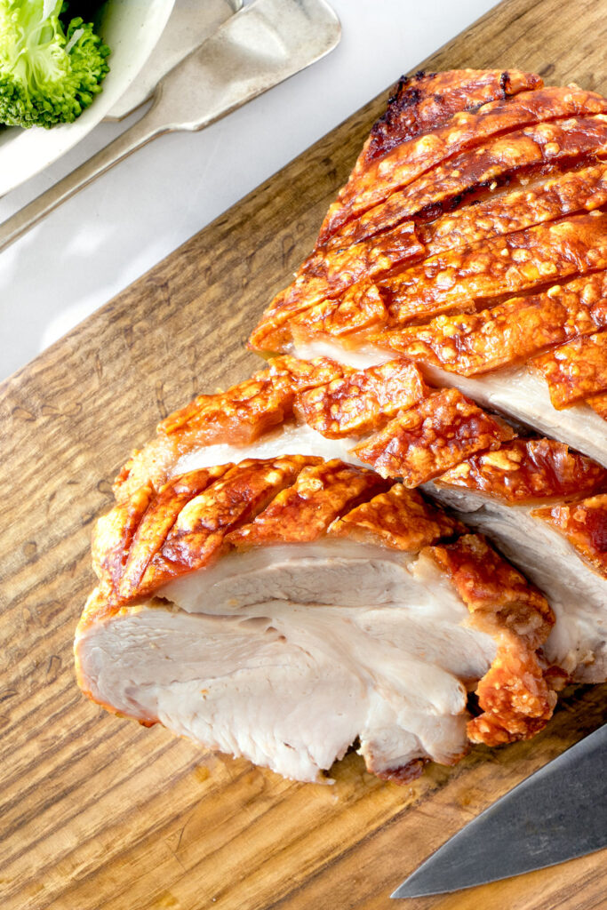 Air fried pork roast sliced on a wooden board.