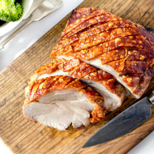 Air fryer roast pork on a wooden board.