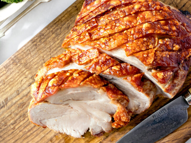 Air fryer roast pork on a wooden board.