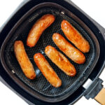 Sausages in air fryer basket.