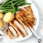 Air fryer chicken steaks on a white plate.