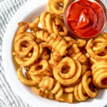 Air fryer curly fries in a white bowl.