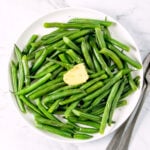 Microwave-steamed green beans on a white plate.