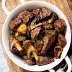 Air fryer steak bites and mushrooms in a white bowl.