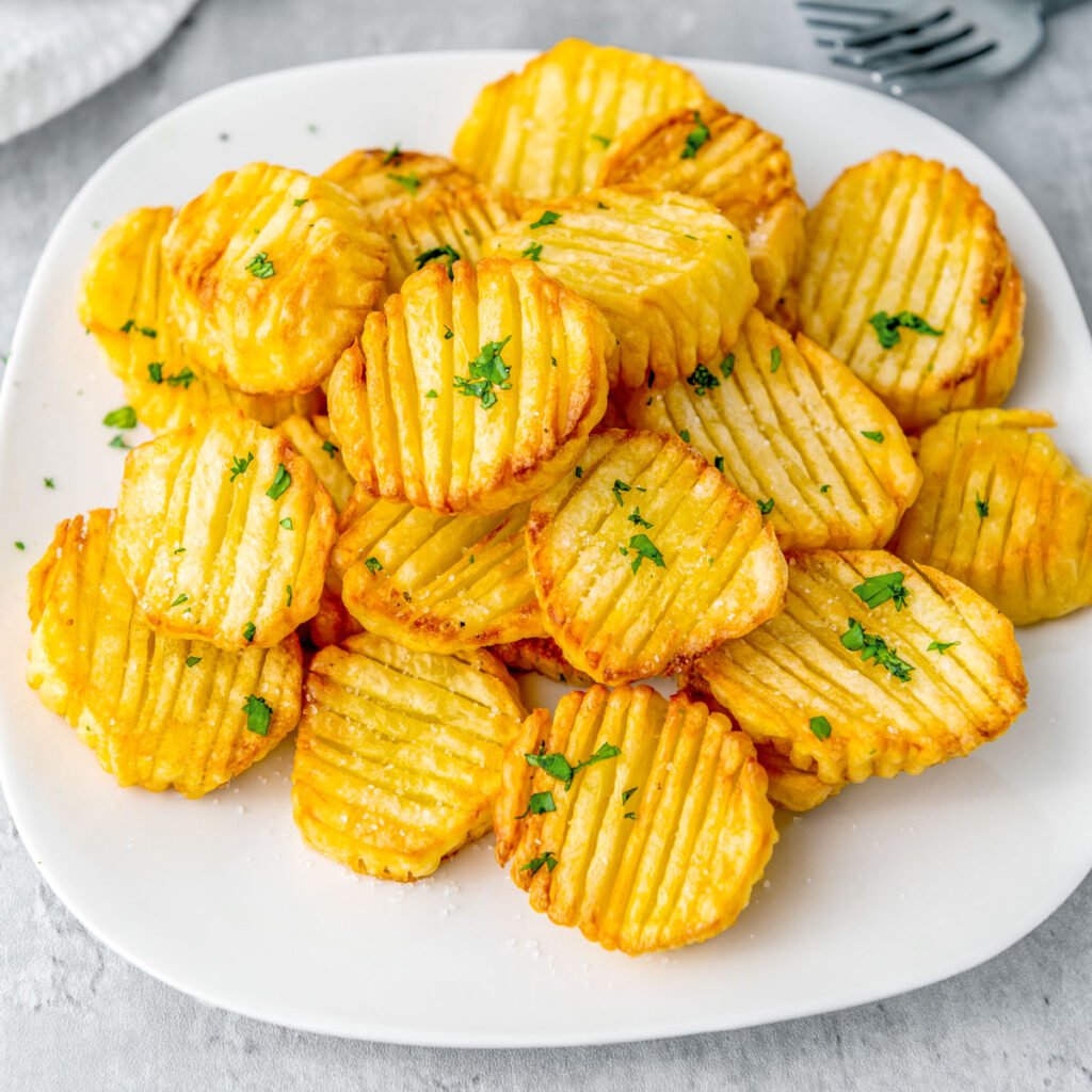 Crunchy golden air fryer accordion potatoes on a white plate.