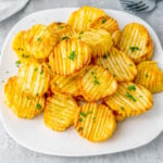Crunchy golden air fryer accordion potatoes on a white plate.