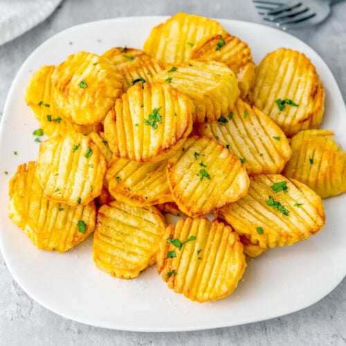 Crunchy golden air fryer accordion potatoes on a white plate.