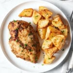 Air fryer chicken breast and potatoes on a white plate.