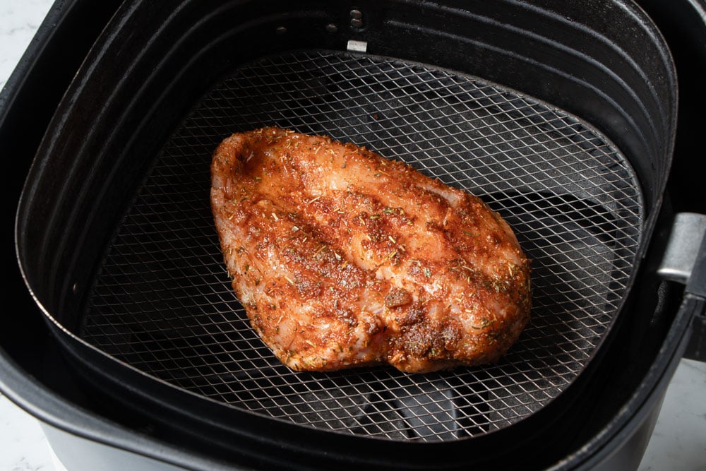 Chicken breast in air fryer basket.