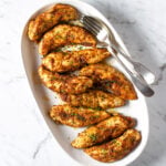 Unbreaded chicken tenders on a white plate.
