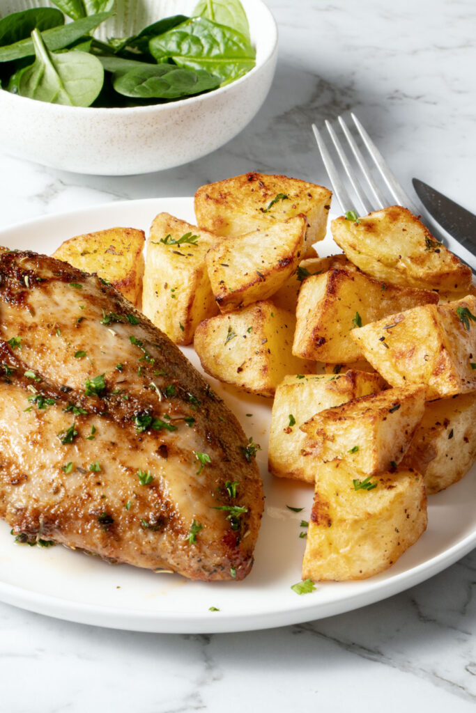 Air fried chicken and potatoes on a white plate.