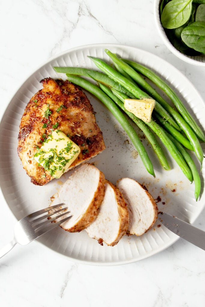 Air fried chicken breast and green beans on a plate.