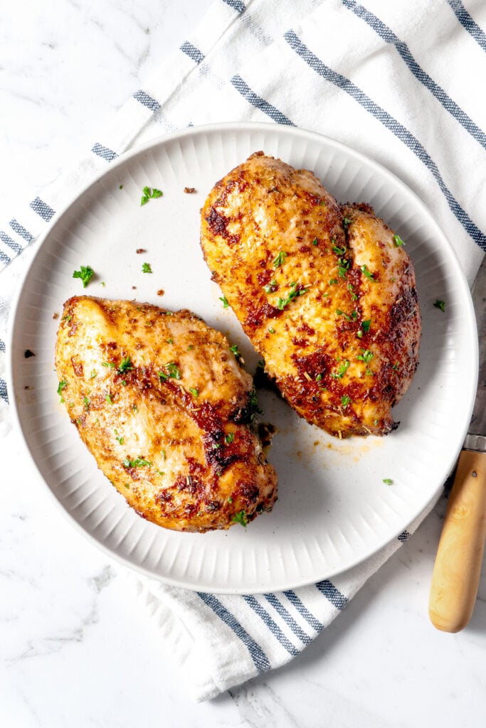 Air fryer chicken breast on a white plate.