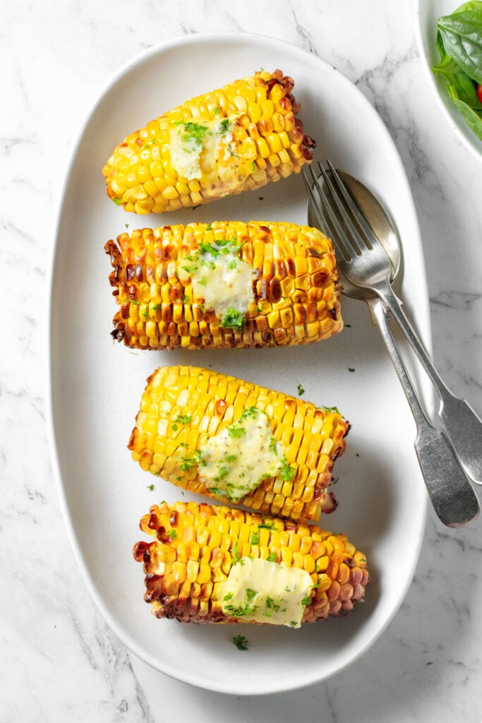 Air fryer corn on the cob on a white plate.