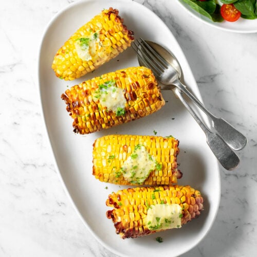 Air fryer corn on the cob on a white plate.