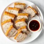 Sliced air fryer pork belly on a white plate.