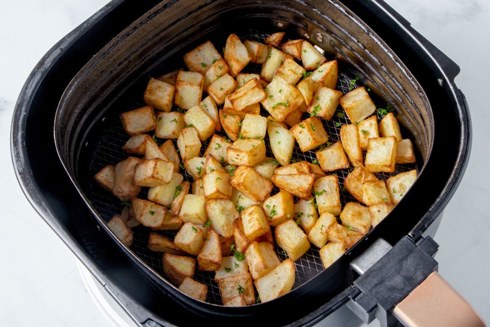 Crispy air fried potato cubes in an air fryer basket.