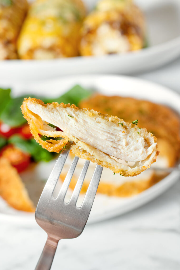A slice of air fried chicken schnitzel on a fork. 