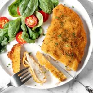 Air fryer chicken schnitzel and salad on a white plate.