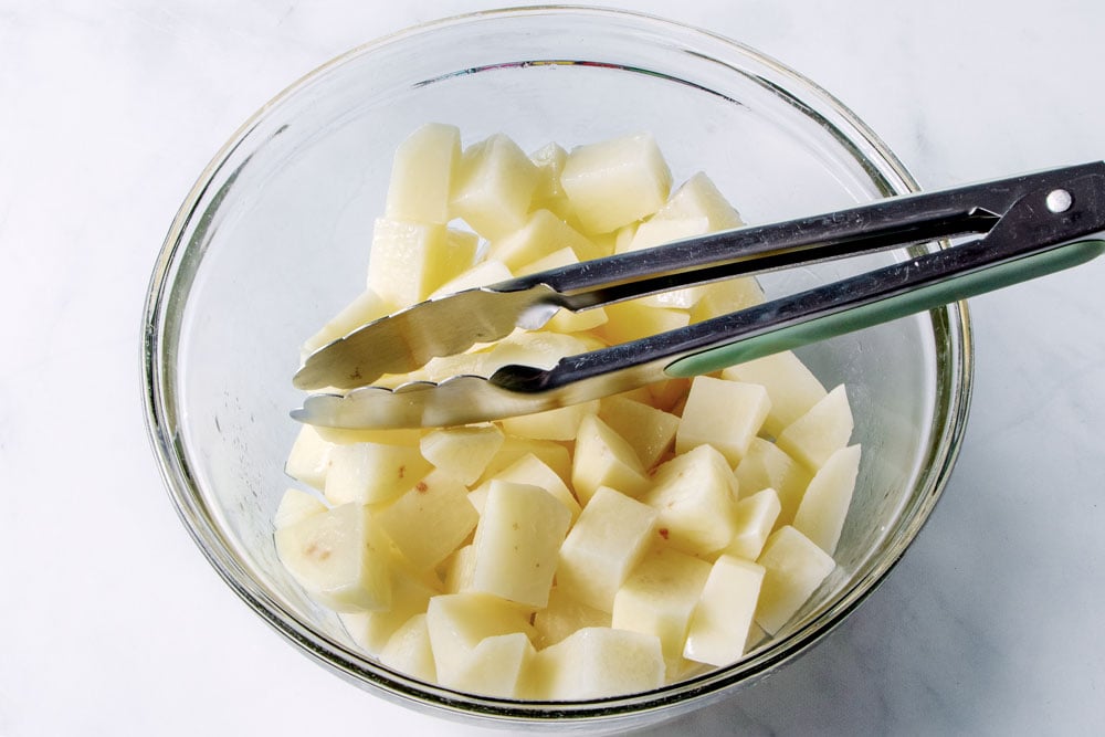Seasoned potato cubes in a glass bowl.