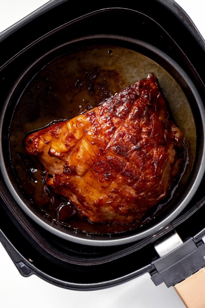 Honey-baked ham in air fryer basket.