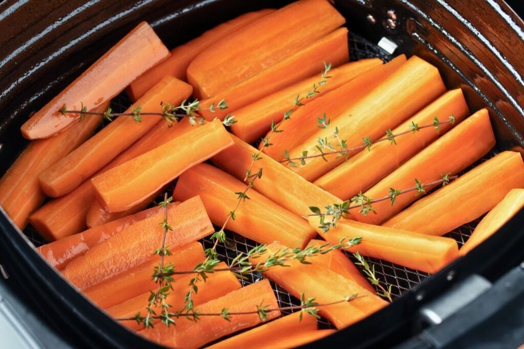 Carrot sticks in air fryer basket. 