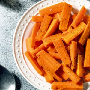Steamed carrots on a white plate.