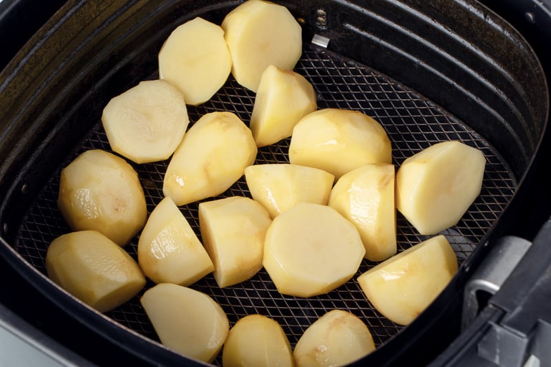 Potato chunks in air fryer basket.