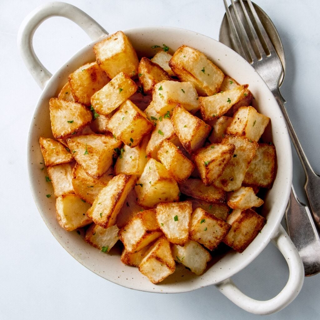 Air fryer potato cubes in a white bowl.