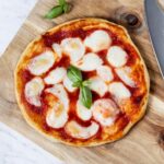 Air fryer pizza on a wooden board.